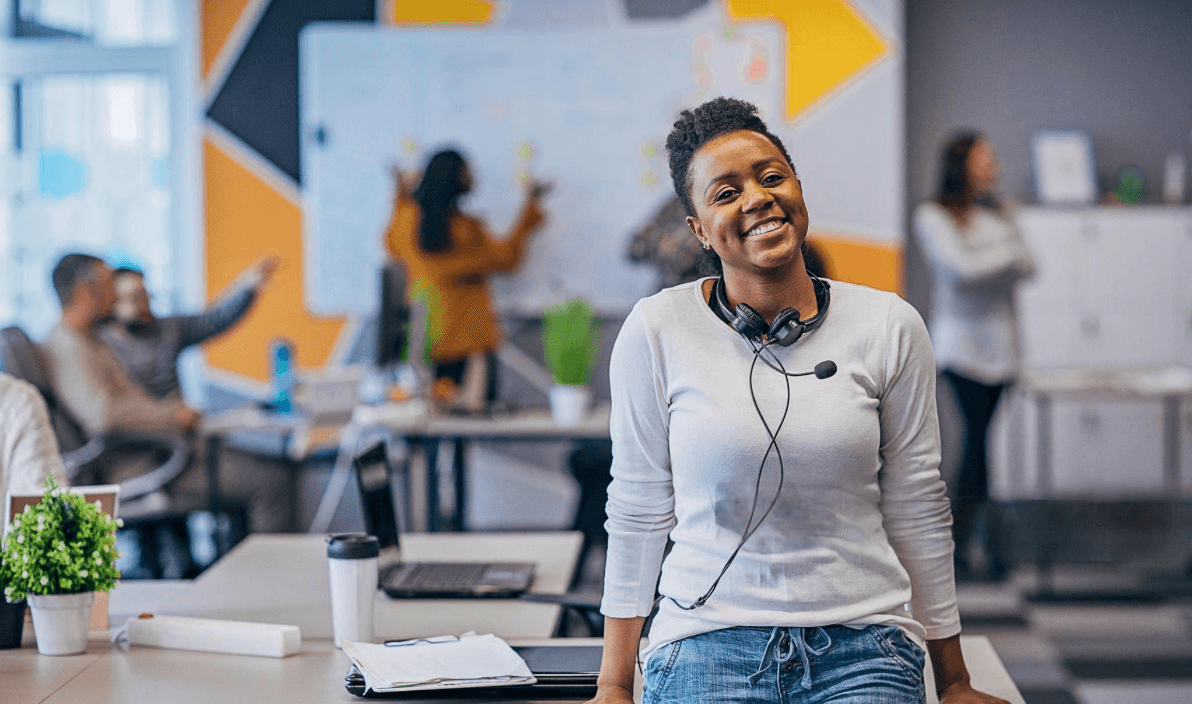 A team member with a headset smiling in a busy office