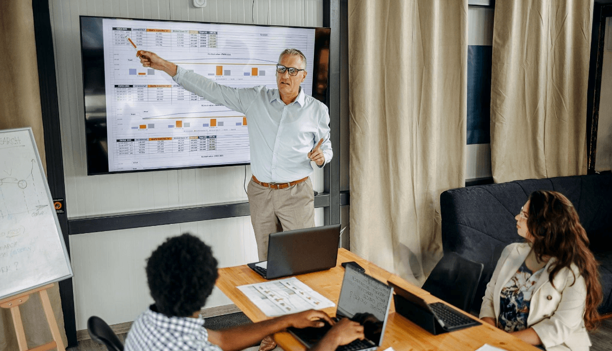 A presenter reviewing data and trends on screen with colleagues